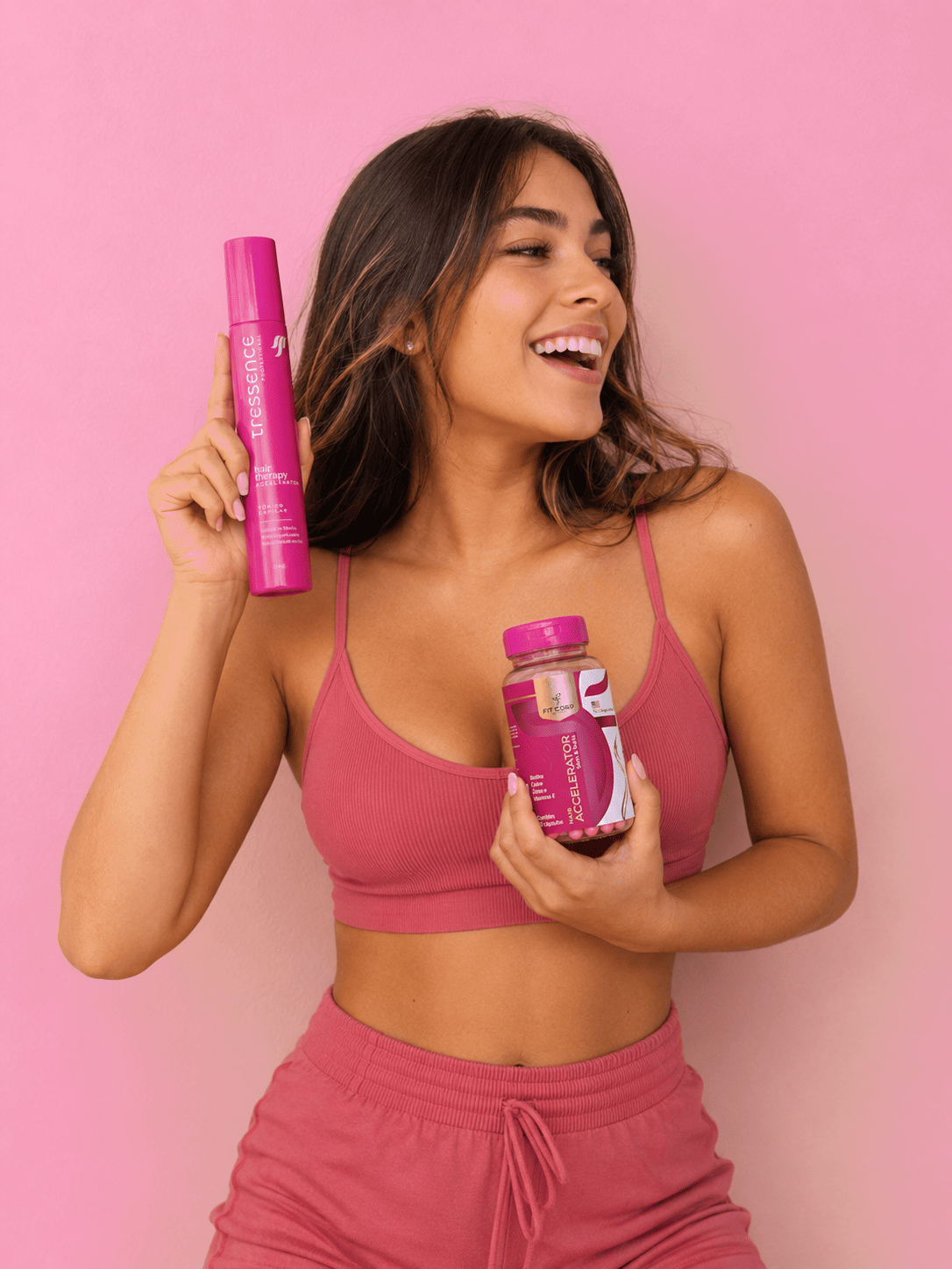 Mulher sorrindo segurando o Tônico Tressence e o frasco do Hair Accelerator